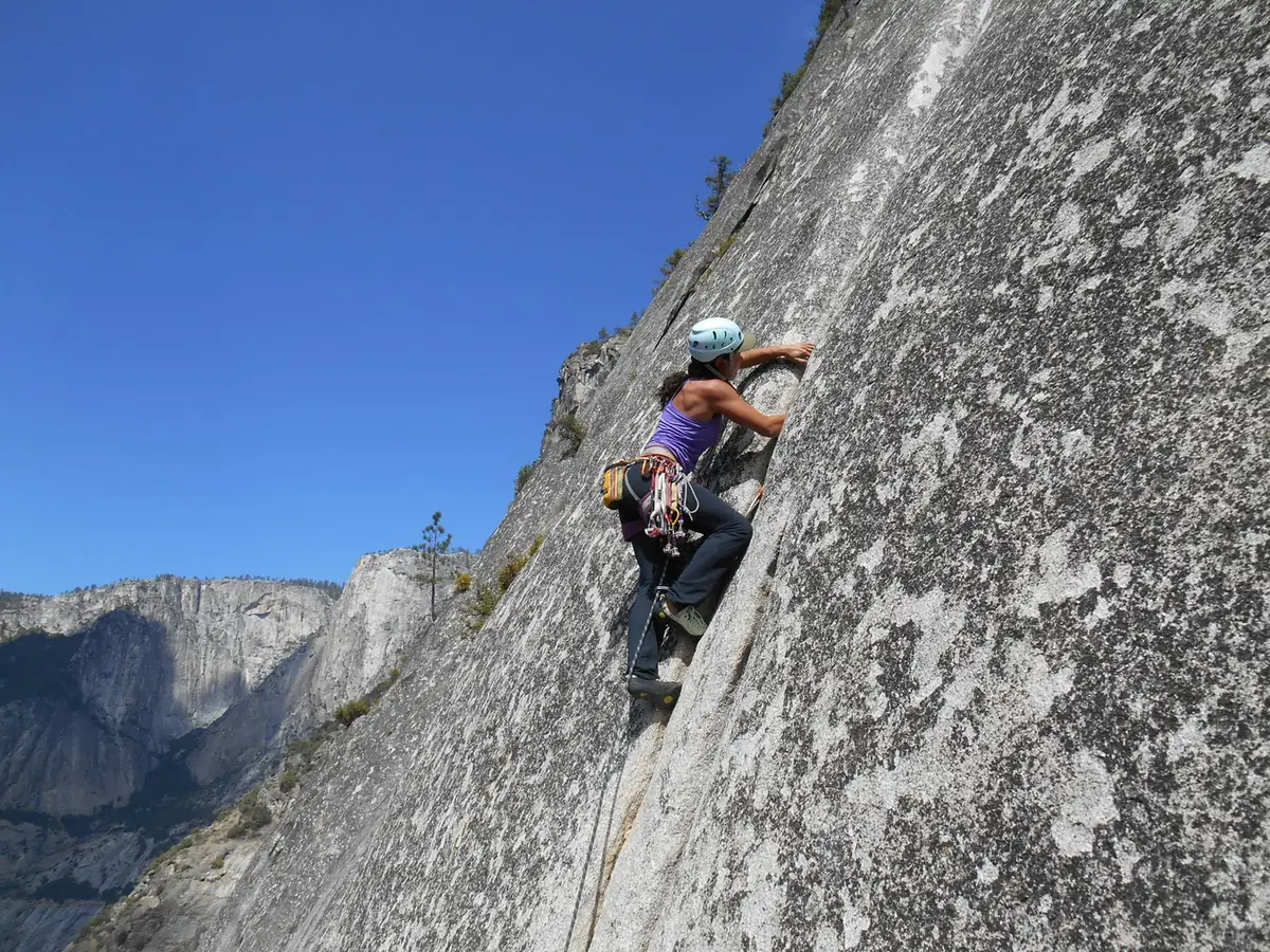 Danielle Pinto escalando uma grande parede de granito sob céu azul