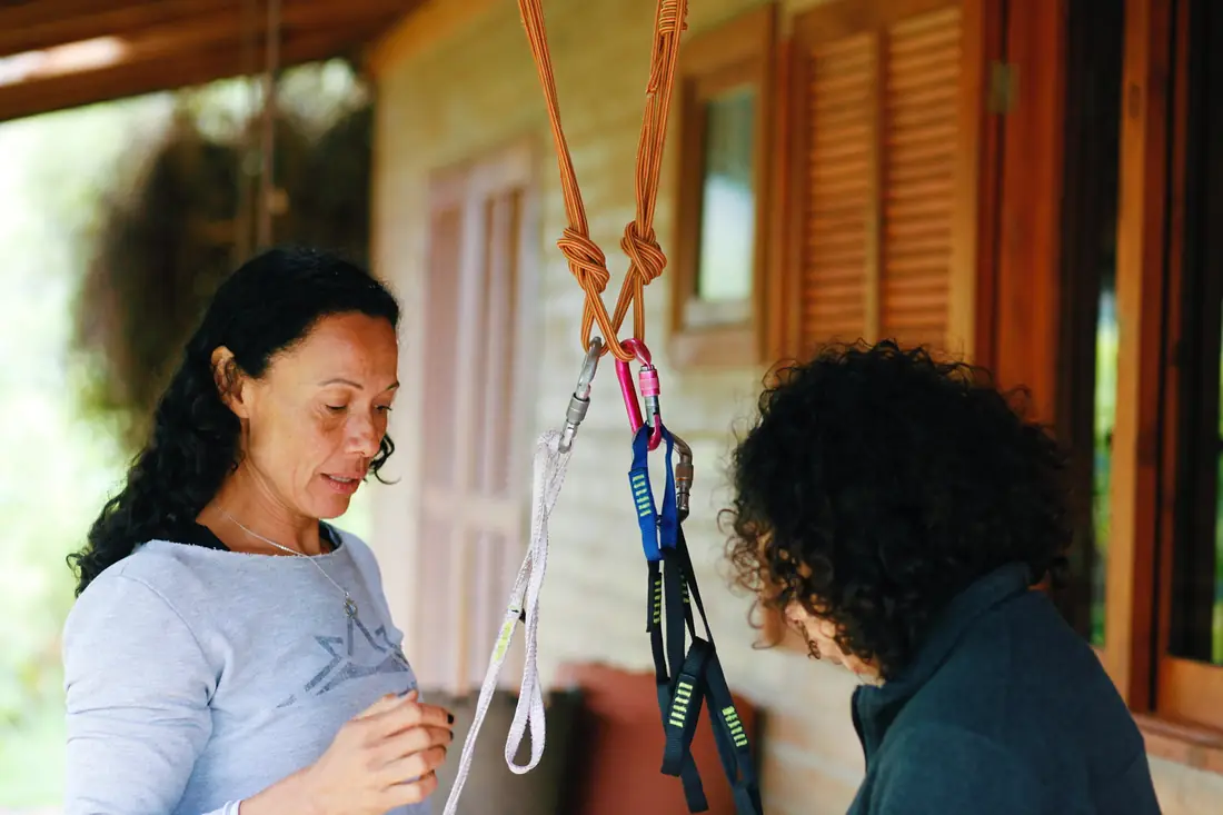 Danielle Pinto ensinando a montagem de uma ancoragem com cordas e fitas durante o encontro indoor