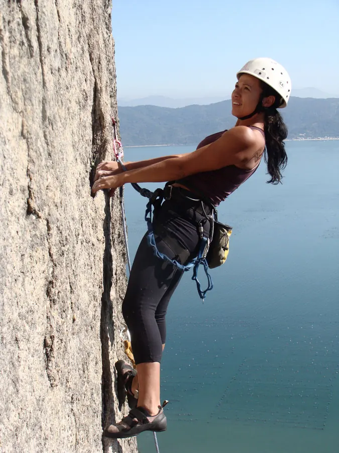 Escaladora em parede de rocha à beira-mar em Florianópolis