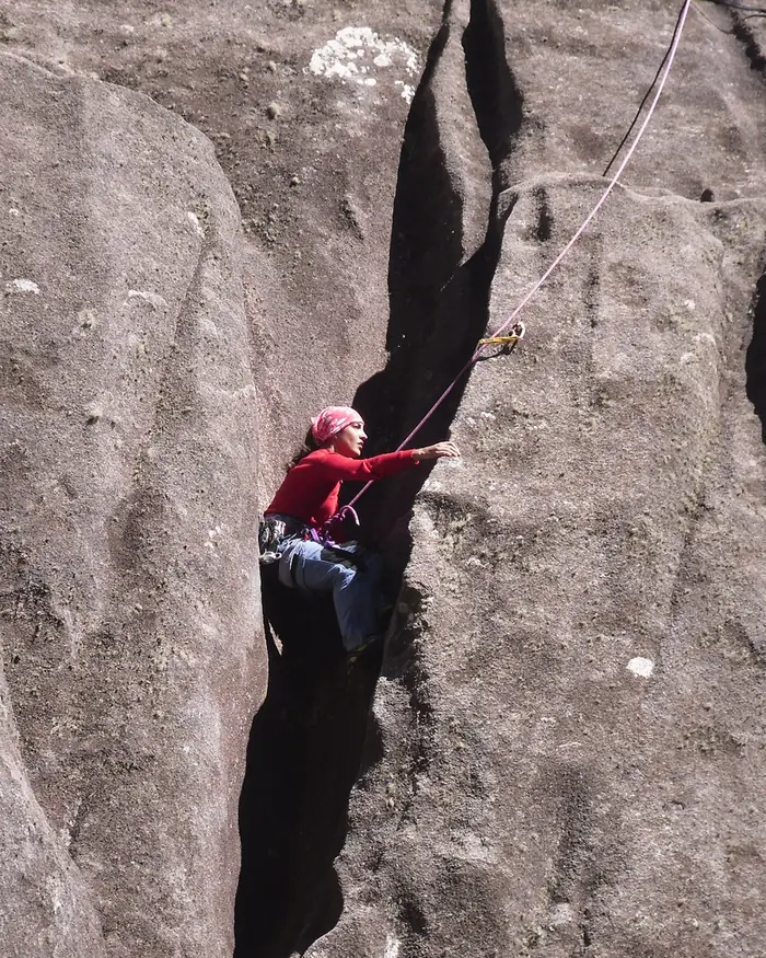 Escaladora subindo uma fenda vertical em parede de rocha no Itatiaia