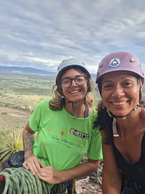 Duas escaladoras sorrindo de capacete com o sertão de Quixadá ao fundo