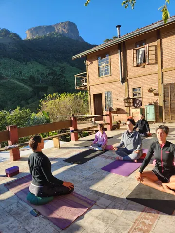 Prática de yoga ao ar livre em frente à hospedagem, com montanhas ao fundo
