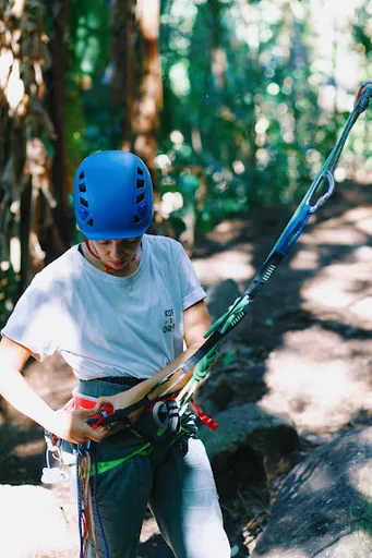 Escaladora de capacete azul organizando a corda e o equipamento