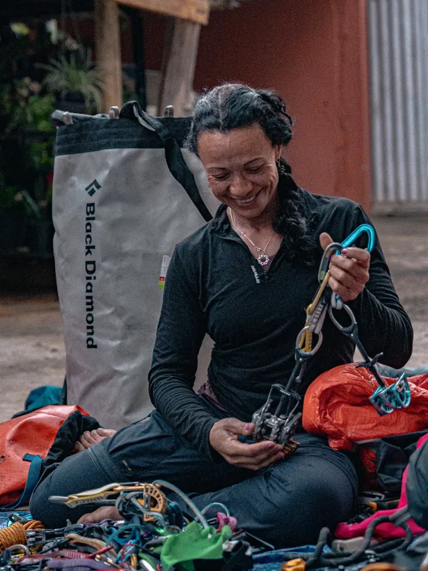 Escaladora sorrindo enquanto organiza móveis e equipamentos de proteção