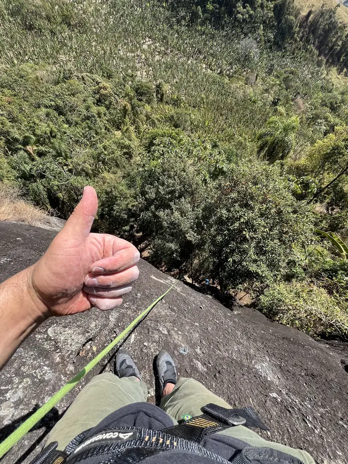 Vista do alto da via: mão fazendo sinal de positivo com a mata lá embaixo